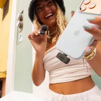 Creator vlogging to her phone with the GoPro wireless mic transmitter in hand and the USB-C Receiver plugged into the phone.