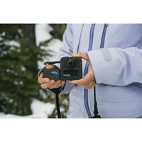 GoPro Rechargeable Enduro Battery for MAX2 being replaced outdoors in a snowy forest.