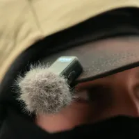 GoPro wireless mic transmitter with windscreen fitted, clipped to the brim of a cap for close-up voice capture.