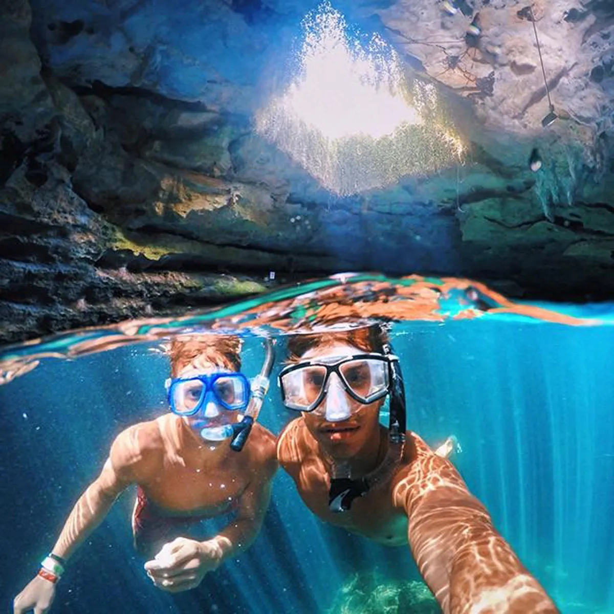 GoPole DOME PRO over/under split shot of snorkellers exploring a cave, above and below the water.