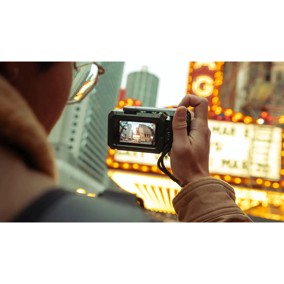GoPro Point-and-Shoot Grip in use on city streets, finger on shutter trigger, wrist strap secured.