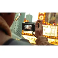 GoPro Point-and-Shoot Grip in use on city streets, finger on shutter trigger, wrist strap secured.